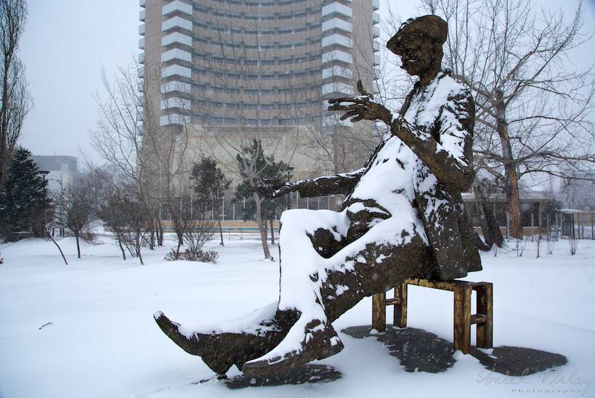 Fotografia statuiei lui Ion Luca Caragiale acoperita de zapada intr-o zi de ianuarie.