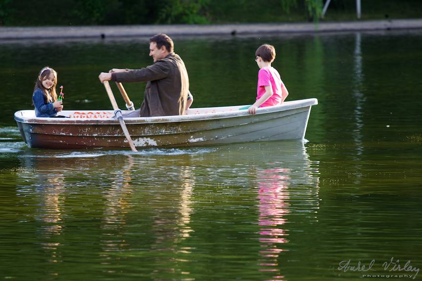 Un tatic mamos plimba copiii cu barca.